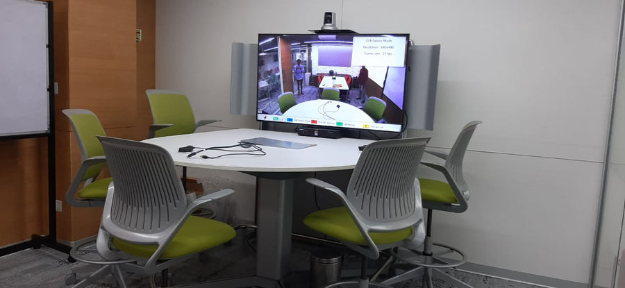 Compact huddle room in India with a round table, an all-in-one video bar, and casual seating for informal video calls