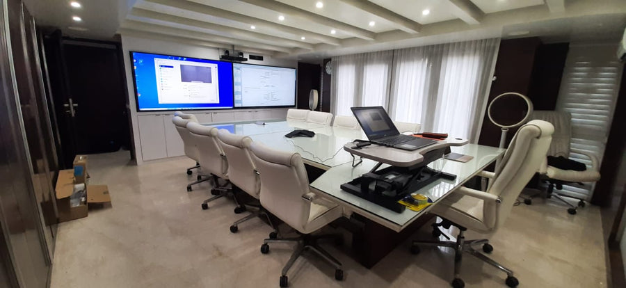 Hybrid meeting room in India with dual displays for video conferencing, a conference table, and ergonomic seating for in-room and remote collaboration