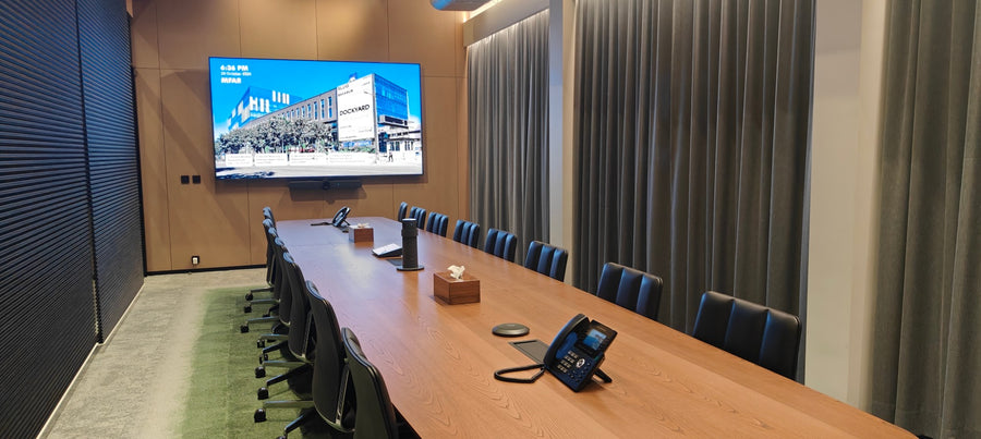 Large meeting room in India with a wall-mounted display, integrated video bar, and a long conference table seating twelve people