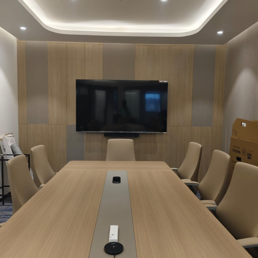 Medium-sized meeting room in India with a wall-mounted display, integrated video bar, and tabletop conference microphone for video conferencing