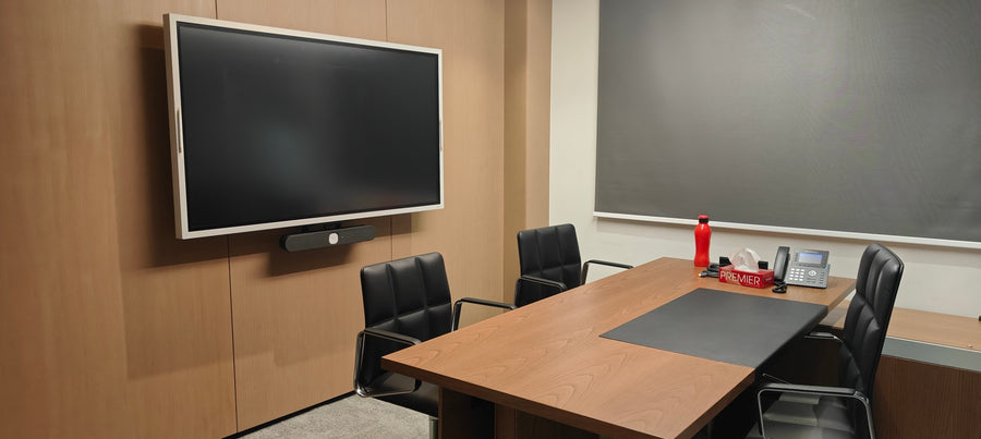 Small meeting room in India with a wall-mounted interactive display, integrated video bar, and a compact conference table with a desk phone